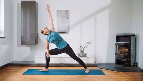 Gabriele führt Utthita Parsvakonasana (Seitliche Winkel) auf der Yogamatte im Wohnzimmer aus